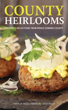 Cover for County Heirlooms: Recipes and Reflections from Prince Edward County; image features two pickerel cakes topped with garnish and a vintage fork.